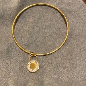 Gold tone bangle bracelet with round disc with stones
